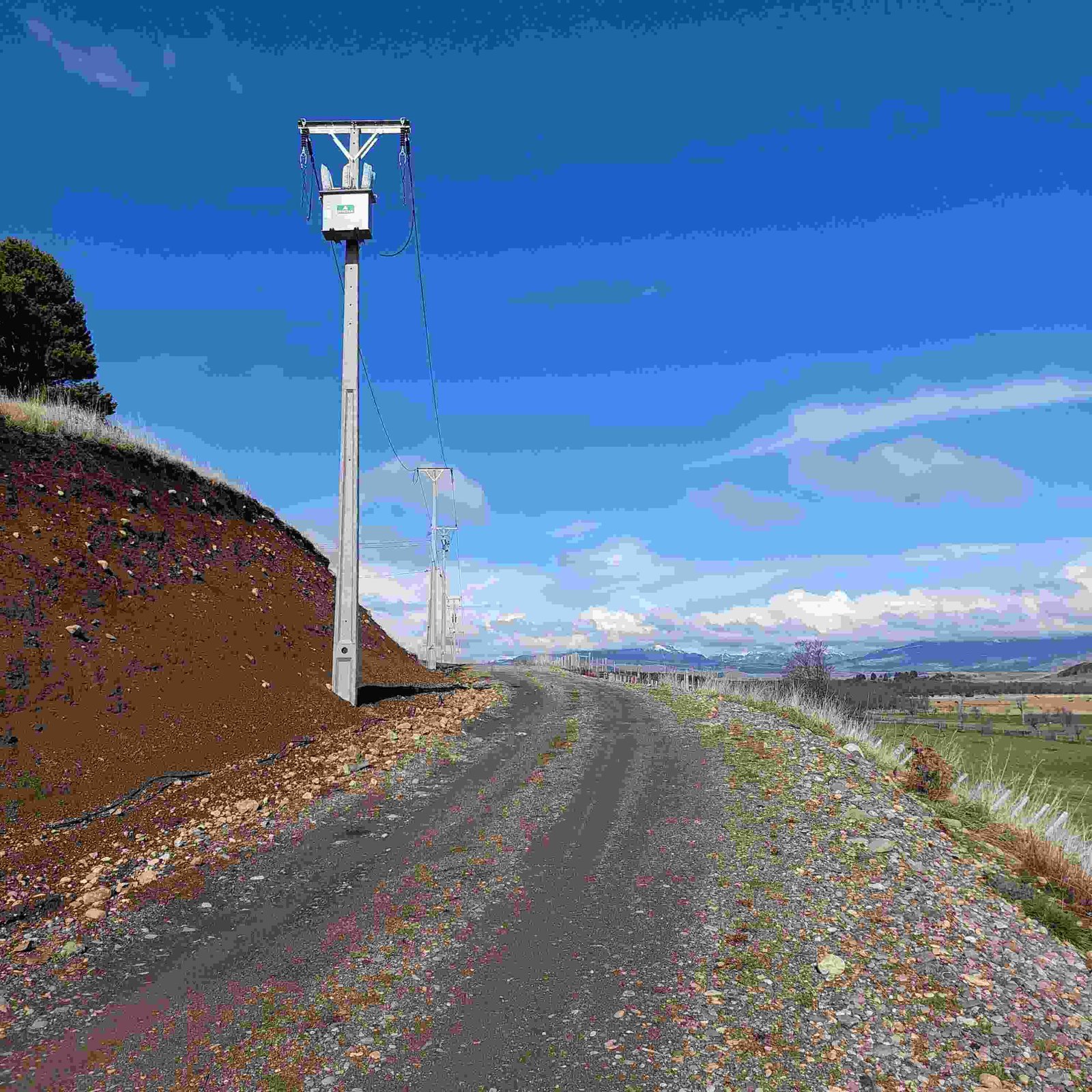 Gravel road with utility poles lining the land parcel, showcasing the property's access to utilities and mountain views.