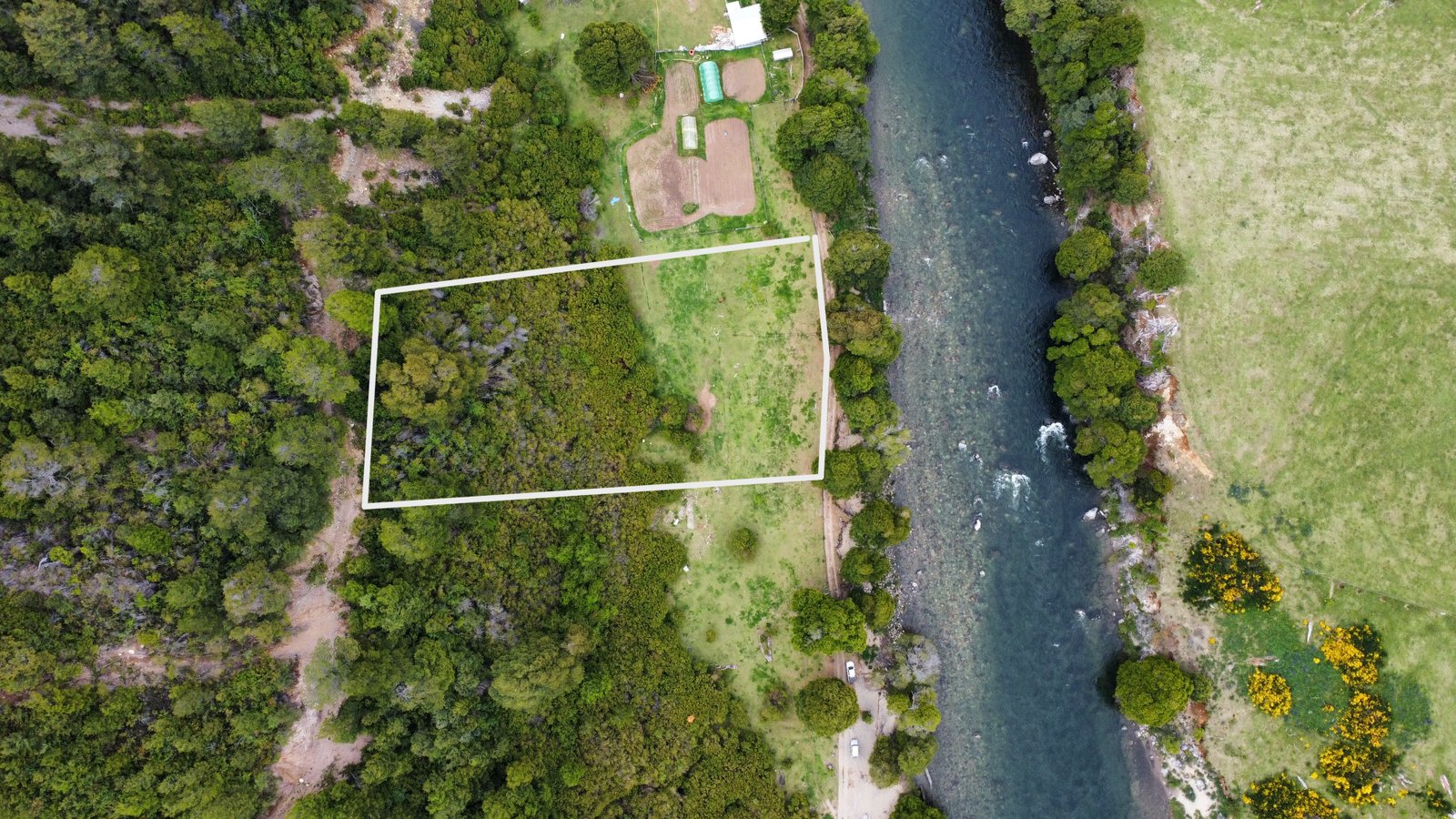Aerial view of the land parcel bordered in white, showing proximity to the river and surrounding trees in Puerto Aysén.
