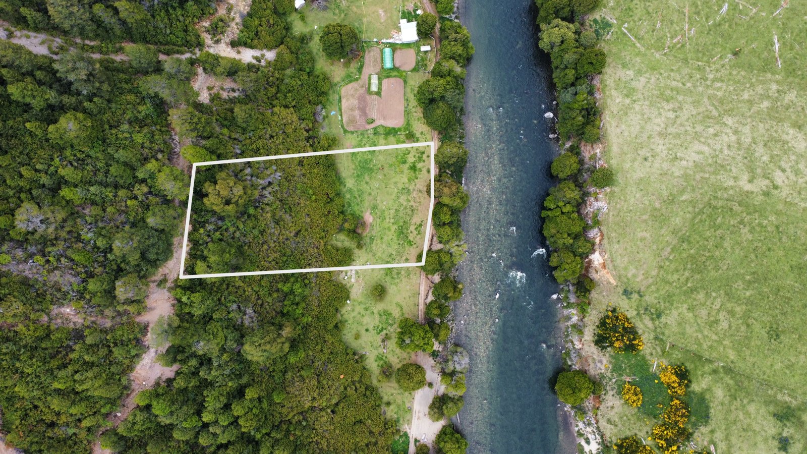 Overhead shot of the land parcel in Puerto Aysén, highlighting its location next to a river and surrounded by lush vegetation.